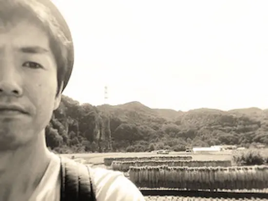 Barber posing outdoors in the mountains, with natural landscape in the background.