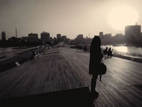 Barber on a dock with water and sky in the background, showcasing a serene atmosphere.